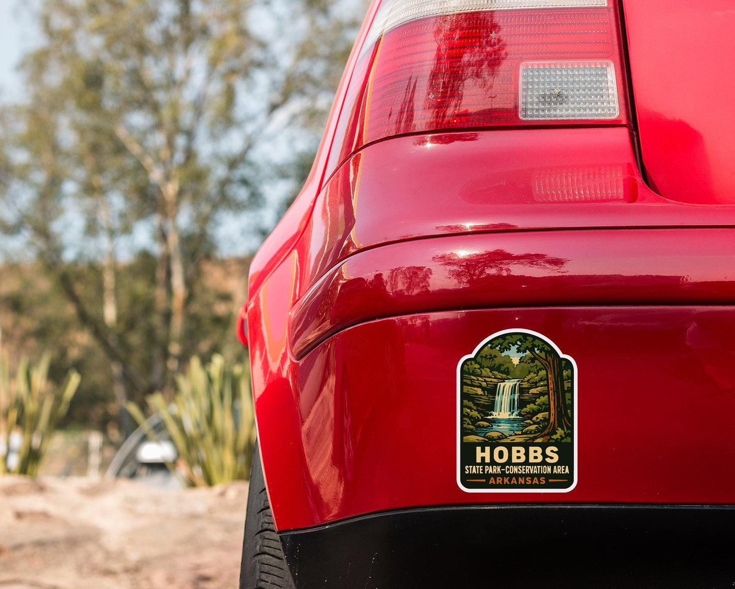 the rear end of a red car with a sticker on the back window that reads "HOBBS STATE PARK-CONSERVATION AREA ARKANSAS".