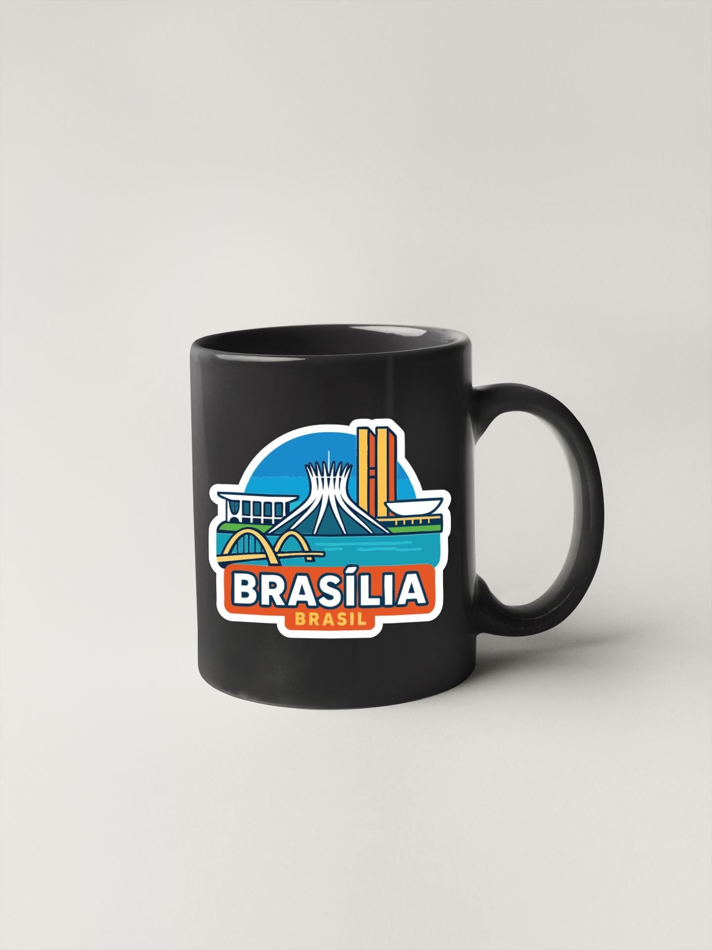 A black coffee mug with a colorful sticker depicting the skyline of Brasilia, the capital city of Brazil.