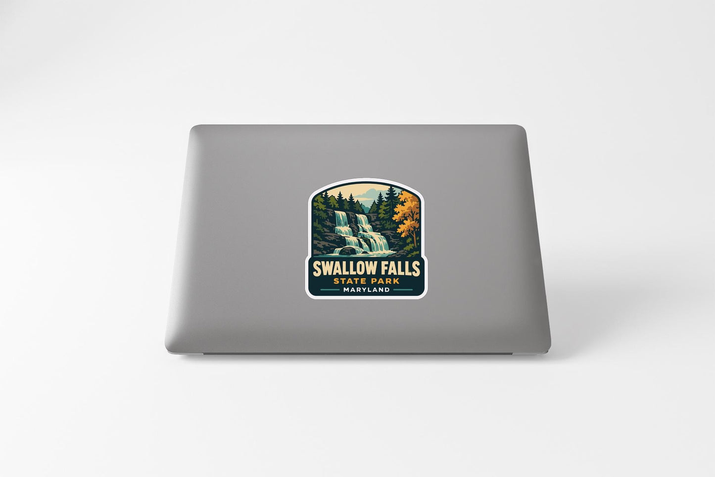 a sticker with a waterfall and trees, placed on the back of a laptop.