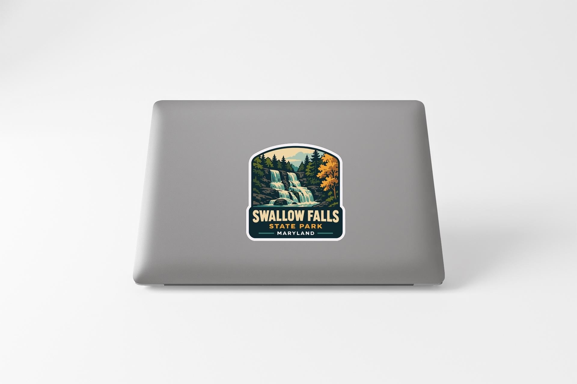 a sticker with a waterfall and trees, placed on the back of a laptop.