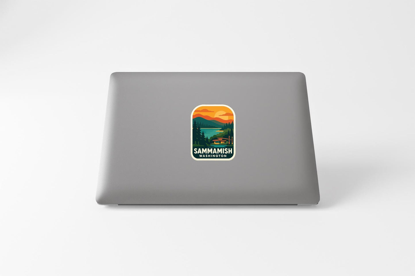 A sticker on the back of a laptop, depicting a scenic landscape with mountains, trees, and a lake.