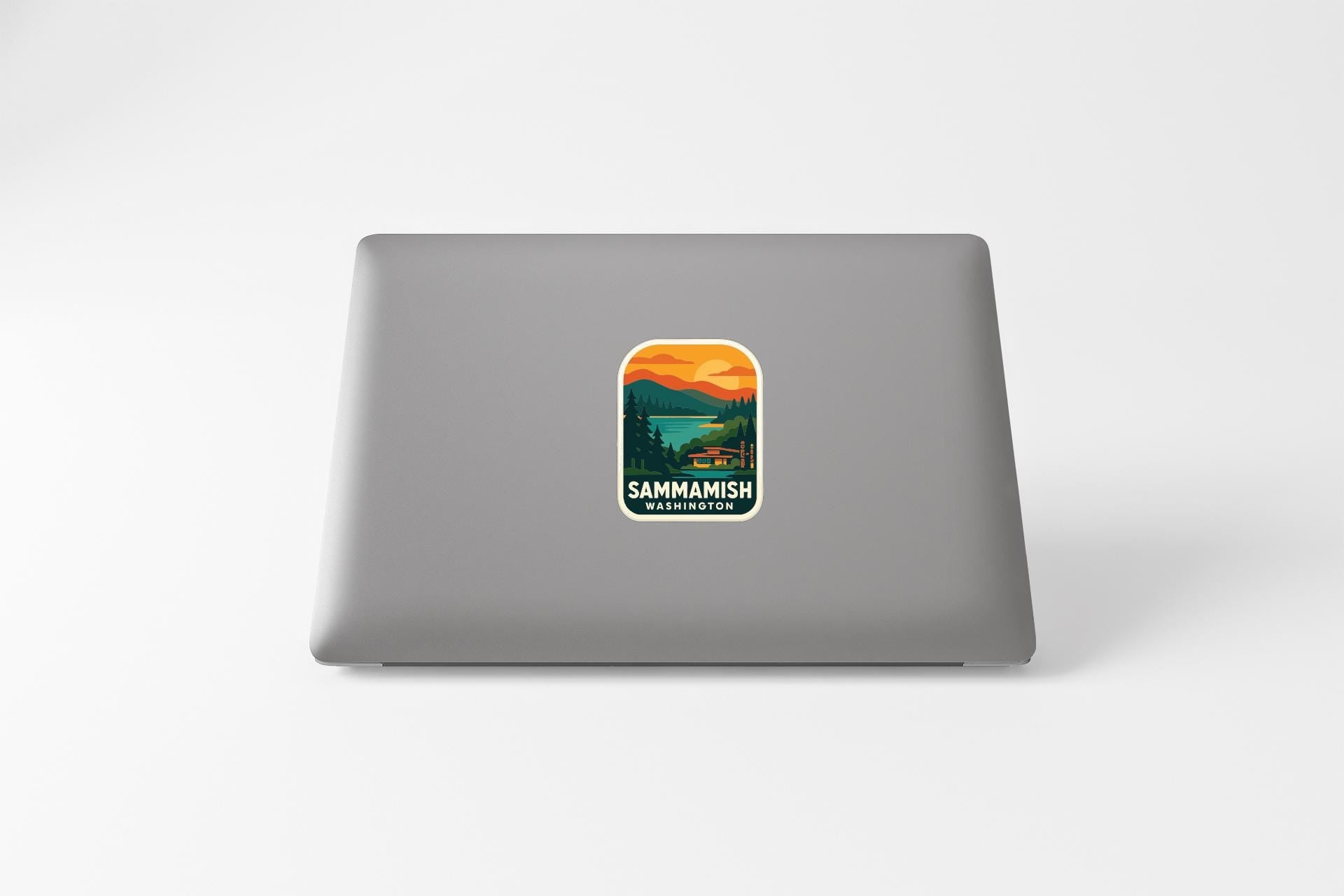 A sticker on the back of a laptop, depicting a scenic landscape with mountains, trees, and a lake.