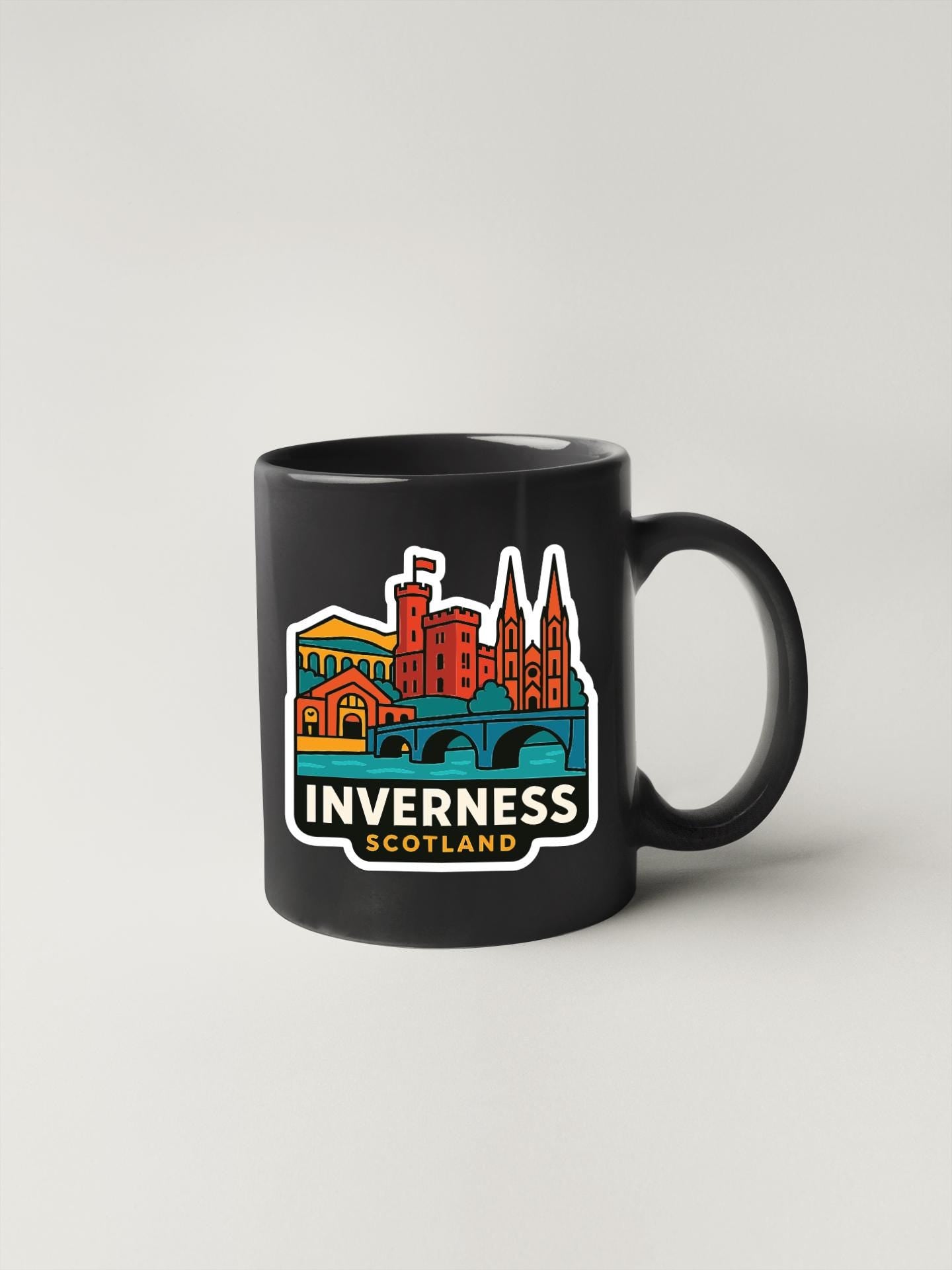 A black coffee mug with a colorful illustration of Inverness, Scotland, featuring various landmarks and buildings.