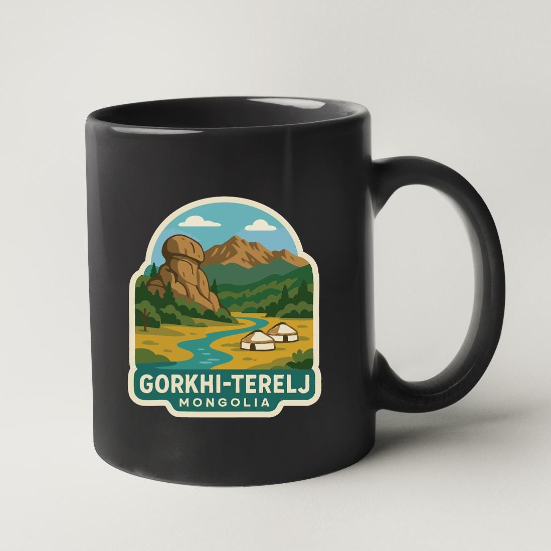 A black coffee mug with a graphic design depicting a mountainous landscape with a river and small settlements.