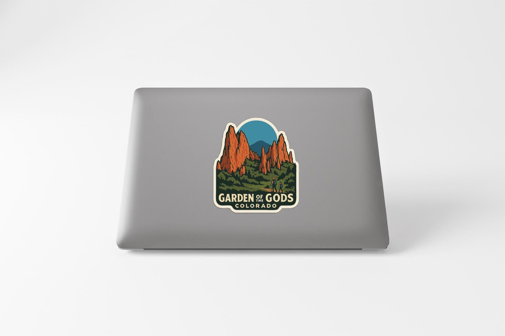 A sticker featuring a mountain landscape with the text "GARDEN OF GODS COLORADO" on a laptop.
