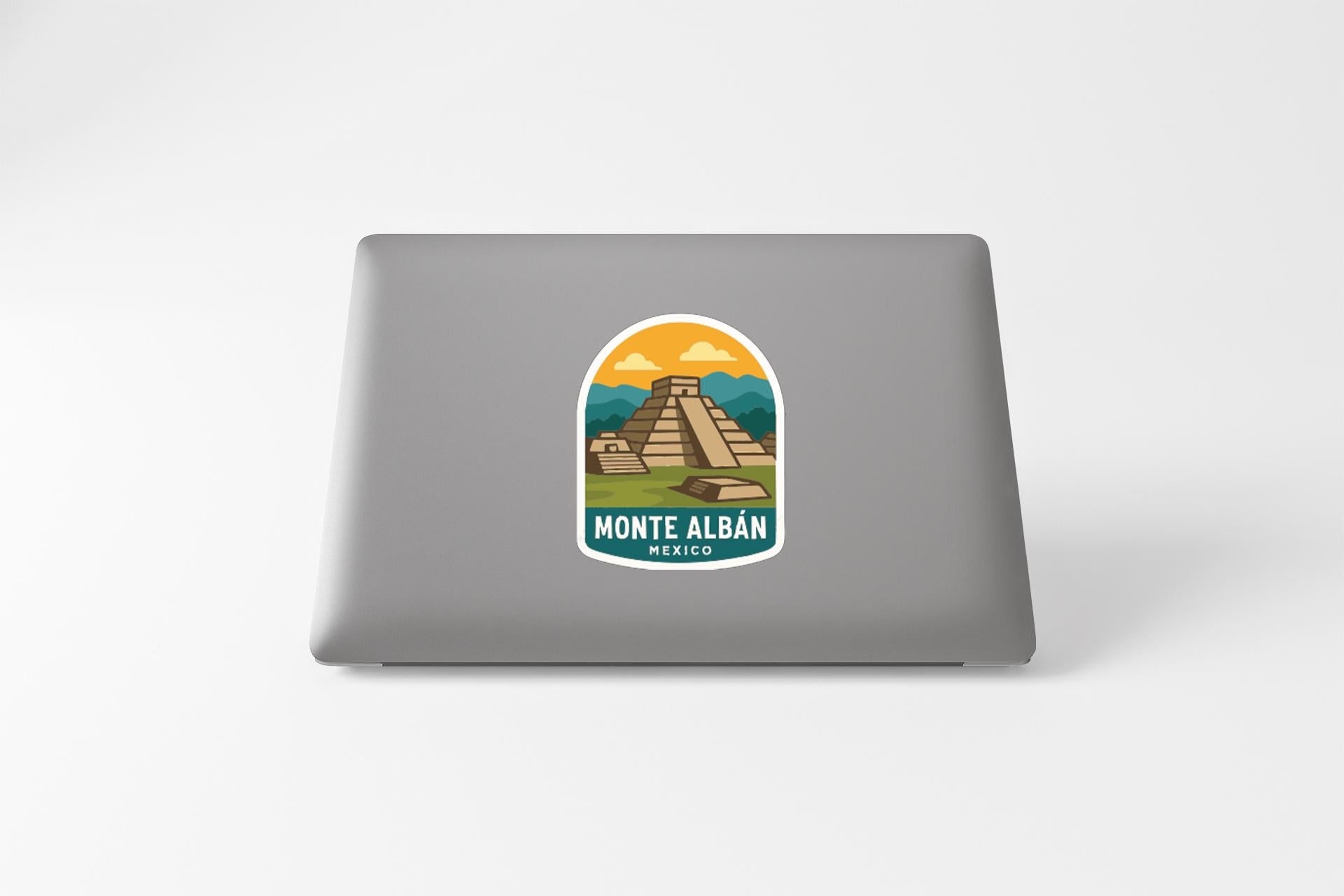 a sticker with a graphic of a pyramid and the text "MONTE ALBAN MEXICO" on a laptop.
