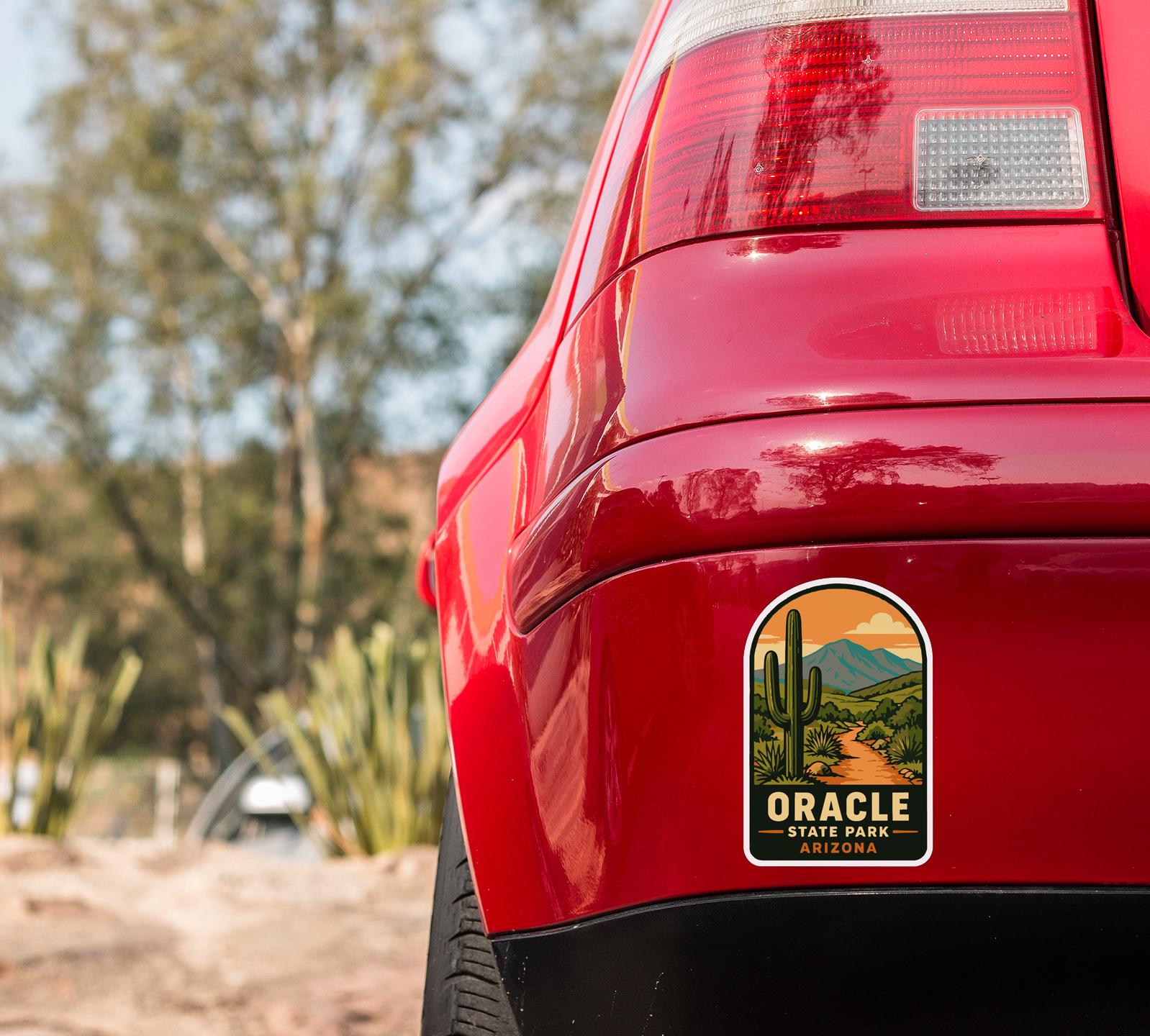 the rear of a red car with a sticker on the back, featuring a desert landscape with a cactus and mountains in the background.