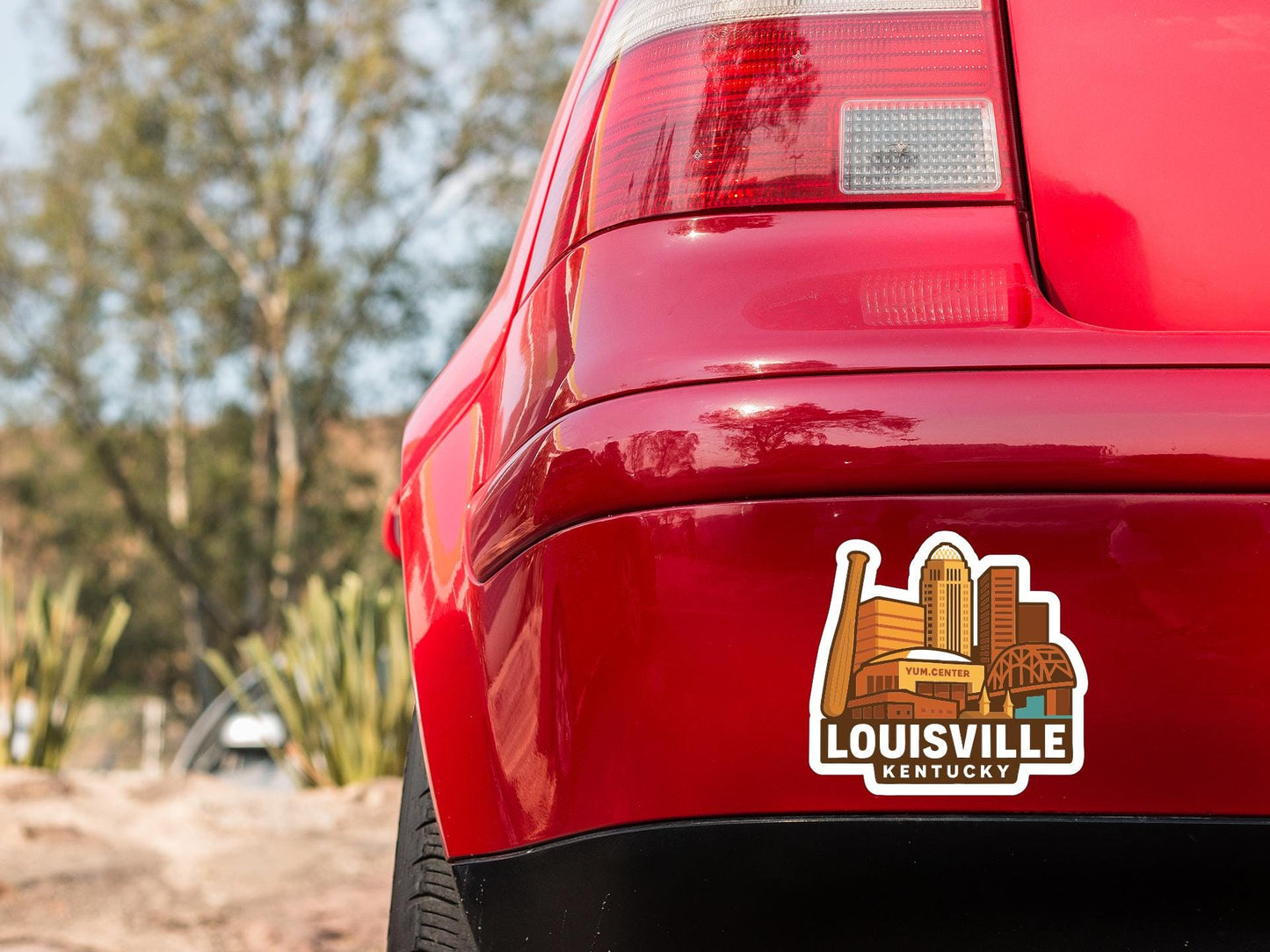 the rear end of a red car with a sticker on the trunk that says "Louisville, Kentucky".