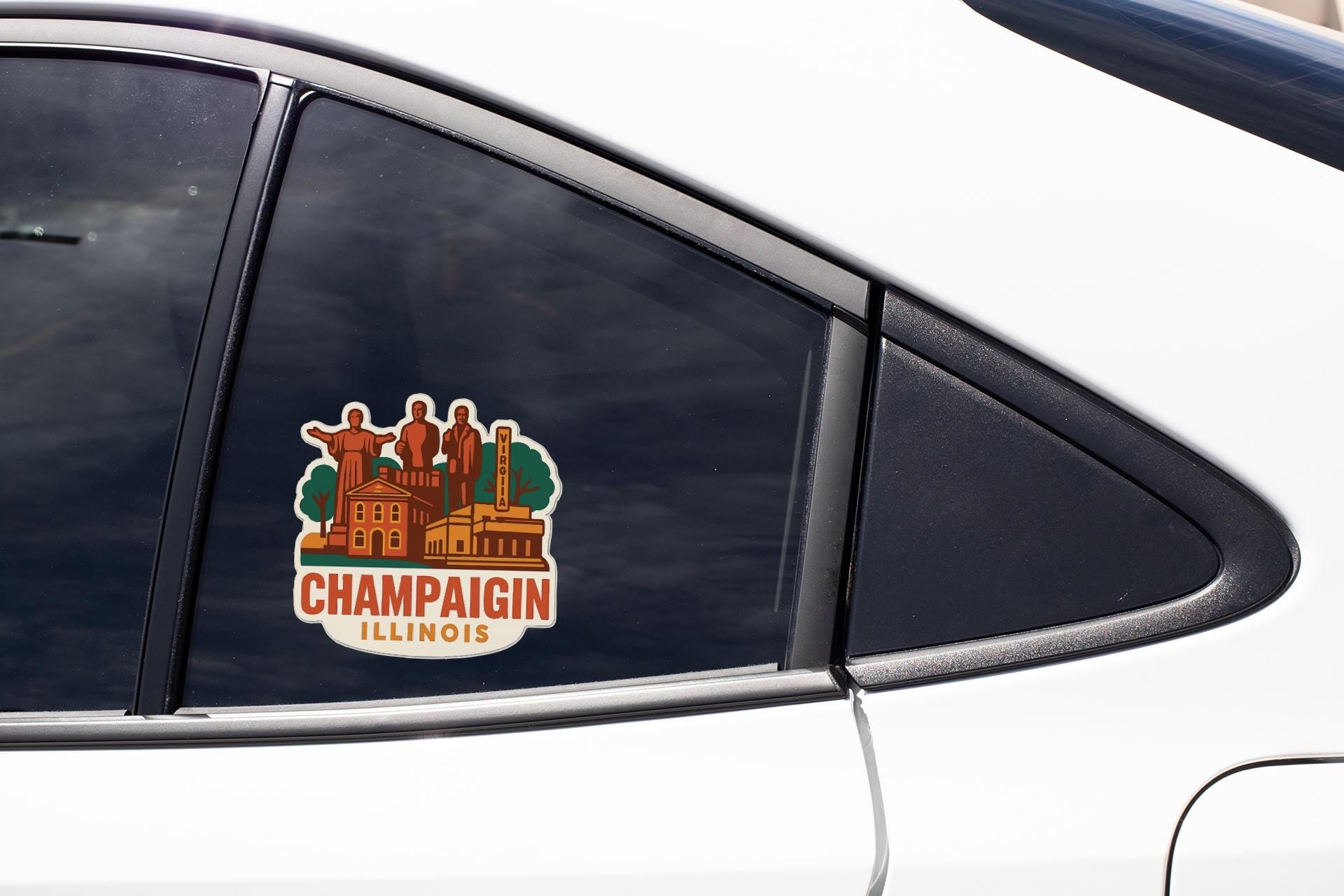 A sticker on the side of a car window, depicting a cityscape with buildings and landmarks, along with the text "CHAMPAGIN ILLINOIS".
