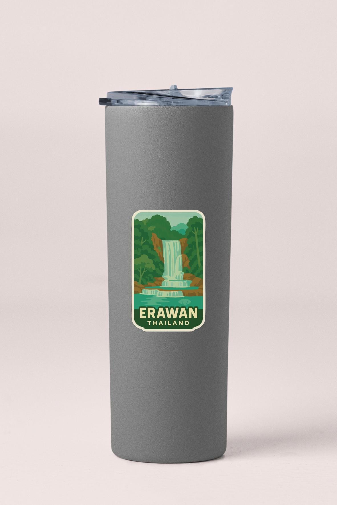 A gray insulated tumbler with a sticker depicting a waterfall in a forested area.