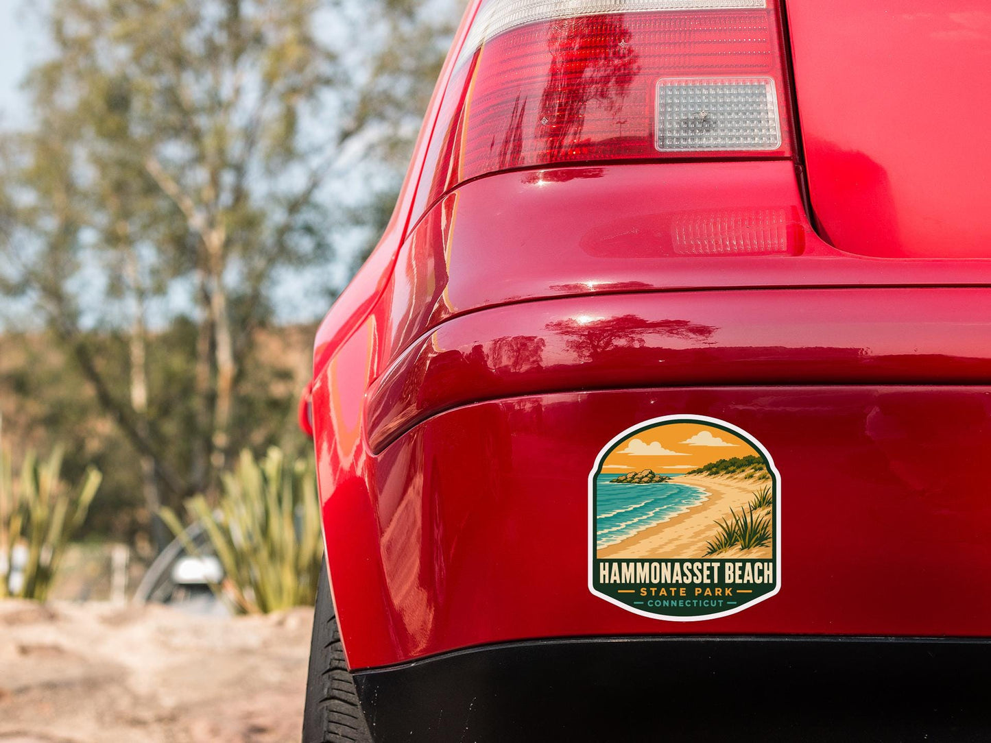 the rear end of a red car with a sticker on the back window that reads "Hammasset Beach State Park Connecticut".