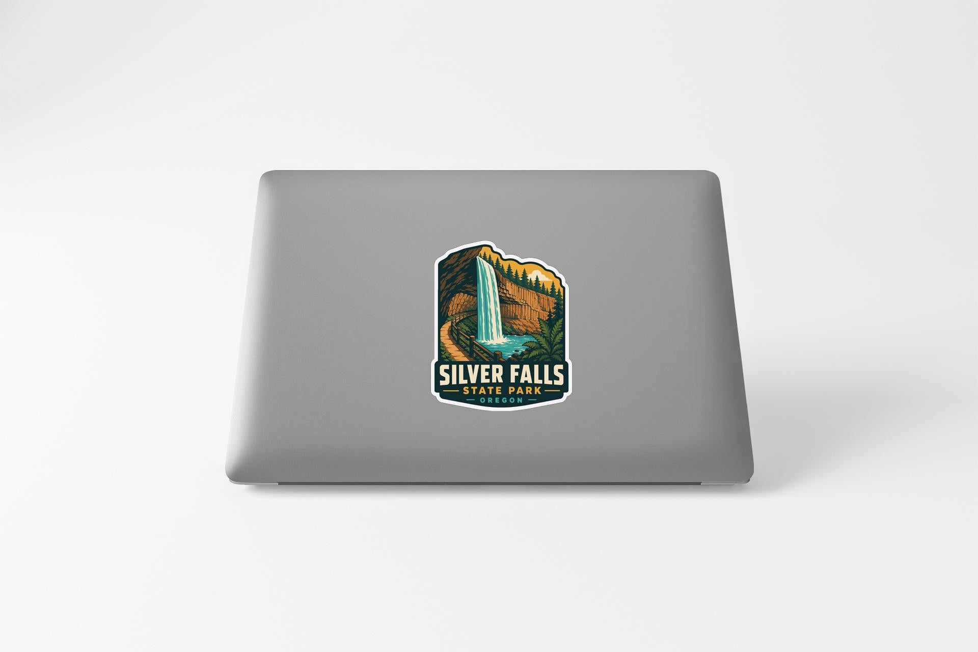 A sticker featuring an illustration of Silver Falls State Park on the back of a laptop computer.