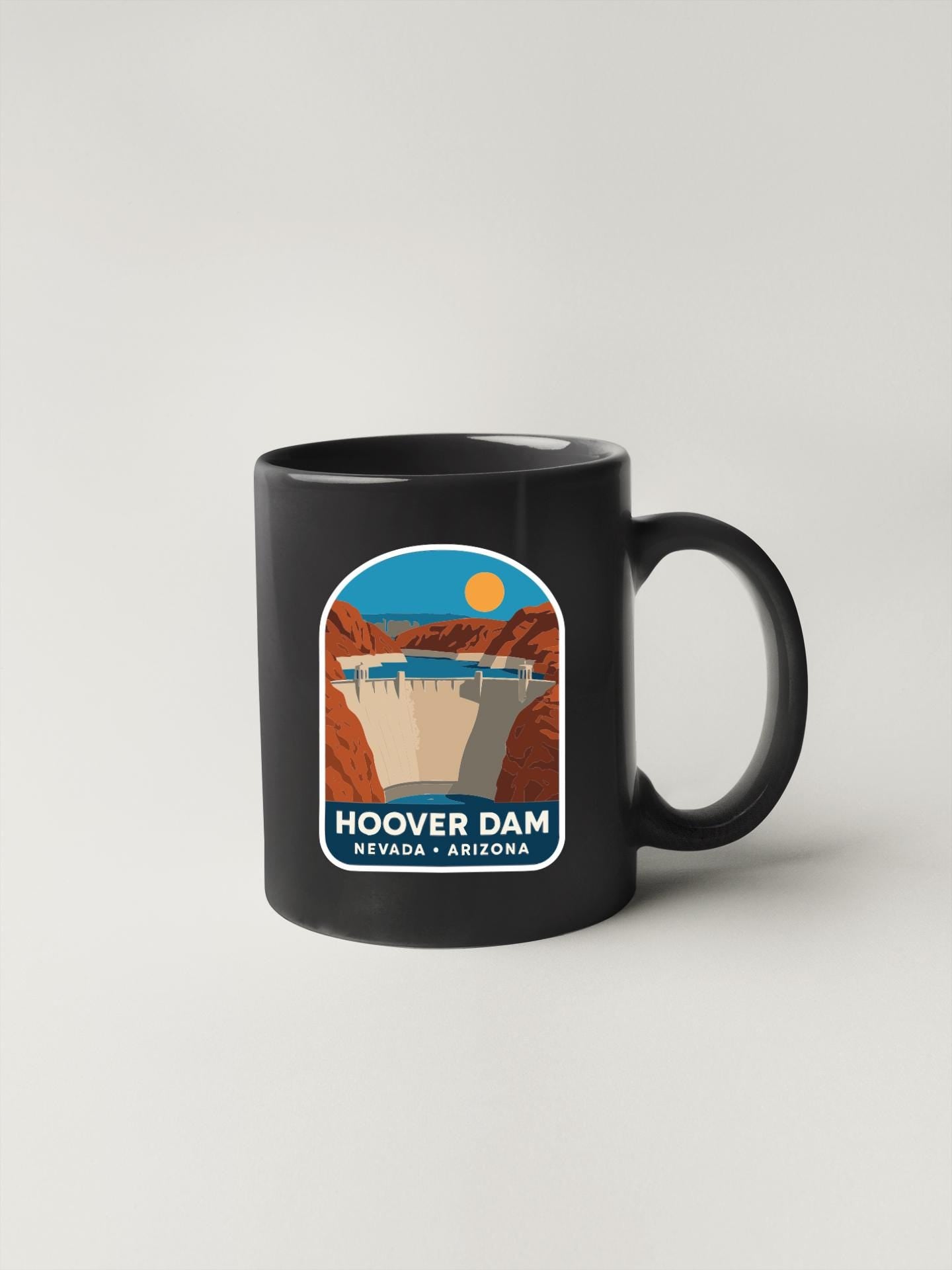 A black coffee mug with a graphic design depicting the Hoover Dam in Nevada, Arizona.
