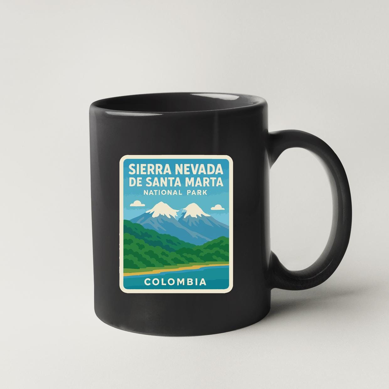 A black coffee mug with a sticker depicting the Sierra Nevada de Santa Marta National Park in Colombia.