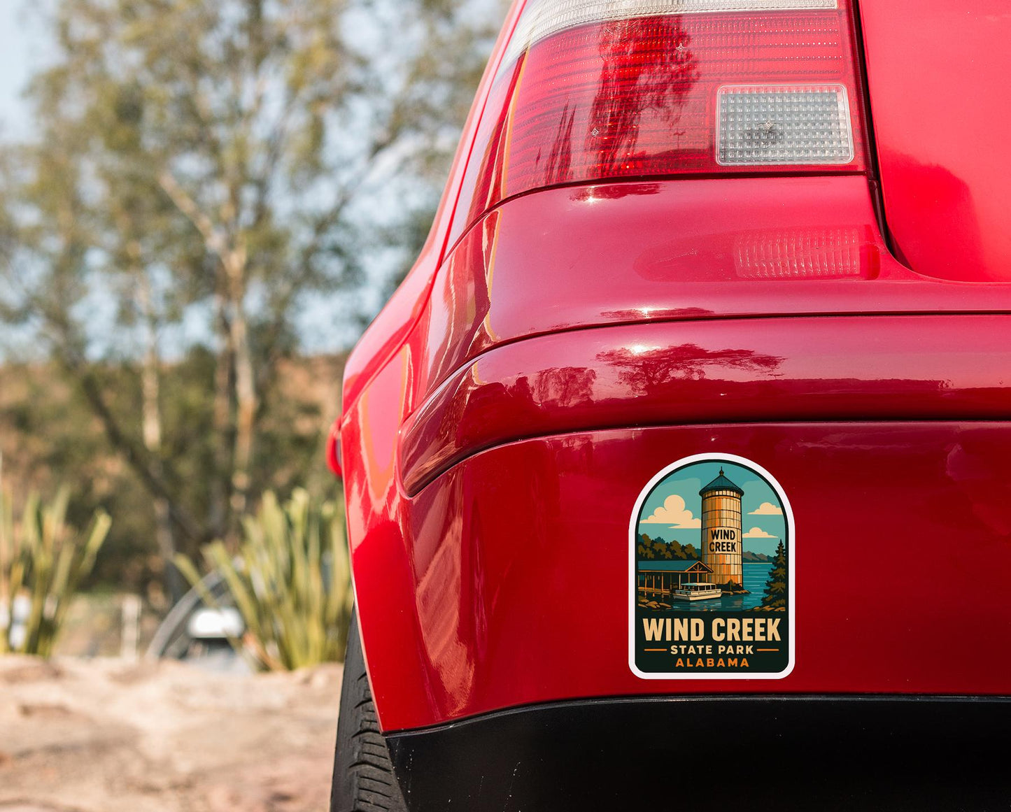 the rear end of a red car with a sticker on the trunk that says "Wind Creek State Park Alabama".