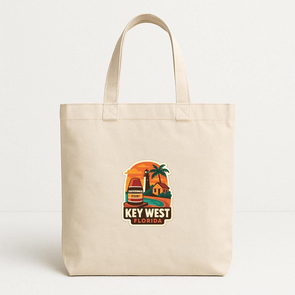 A beige tote bag with a printed design depicting a tropical beach scene, including a lighthouse, palm trees, and a sunset.