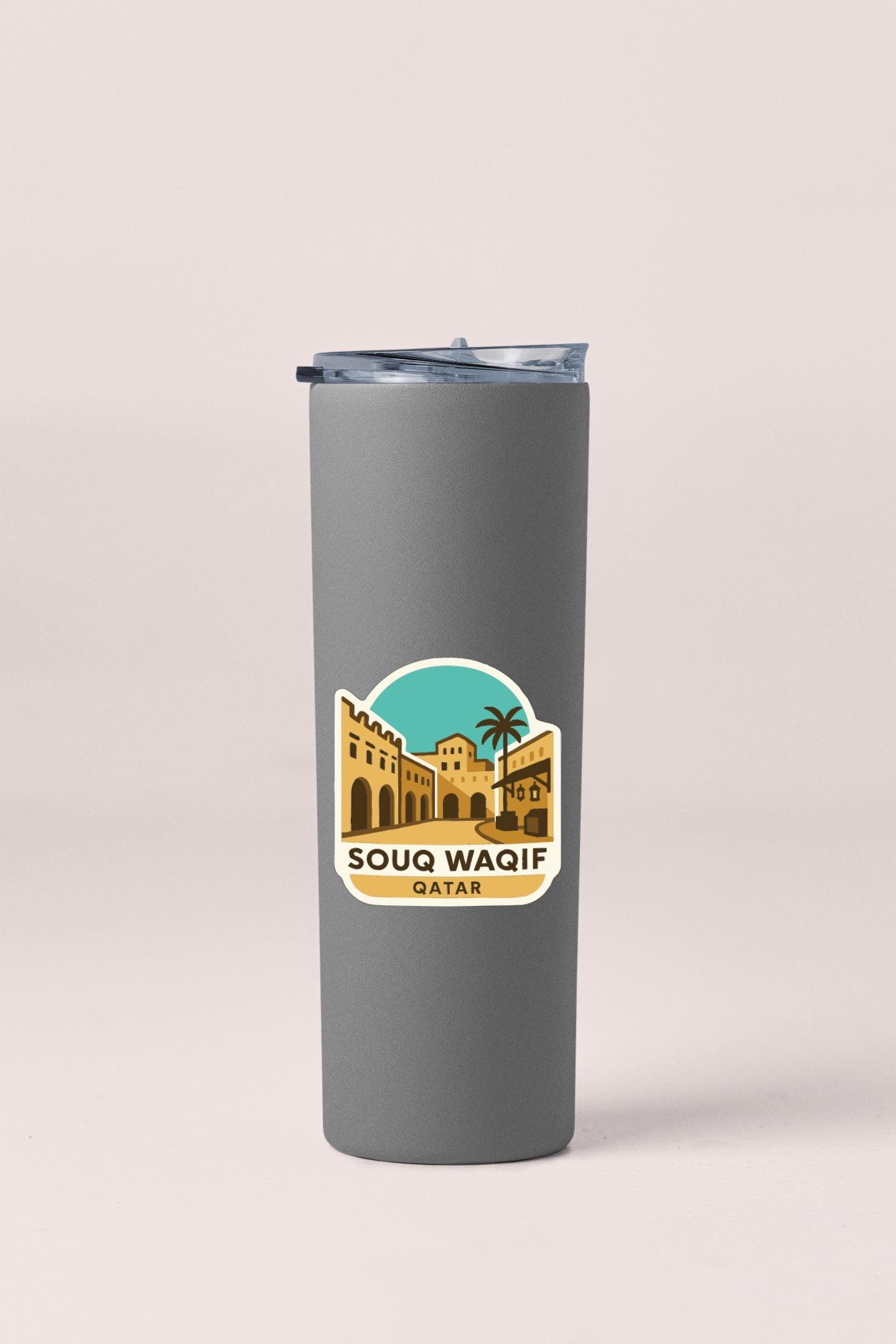 A gray insulated tumbler with a sticker depicting a cityscape and the text "SOUQ WAQIF QATAR" printed on it.