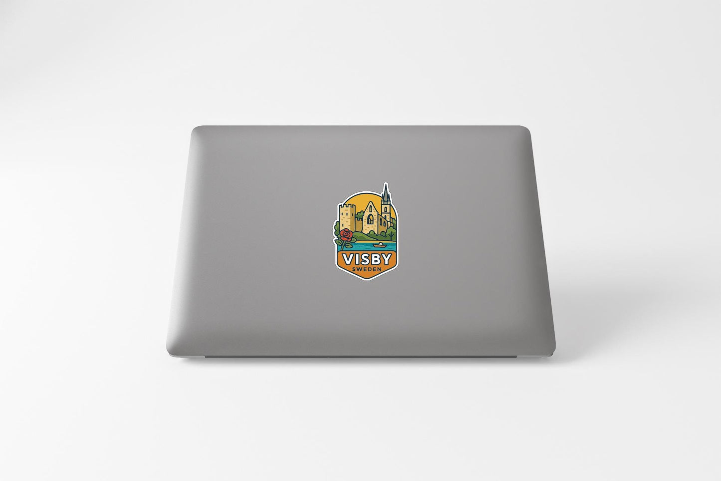a sticker on the back of a laptop with a graphic design depicting a castle and a yellow building.