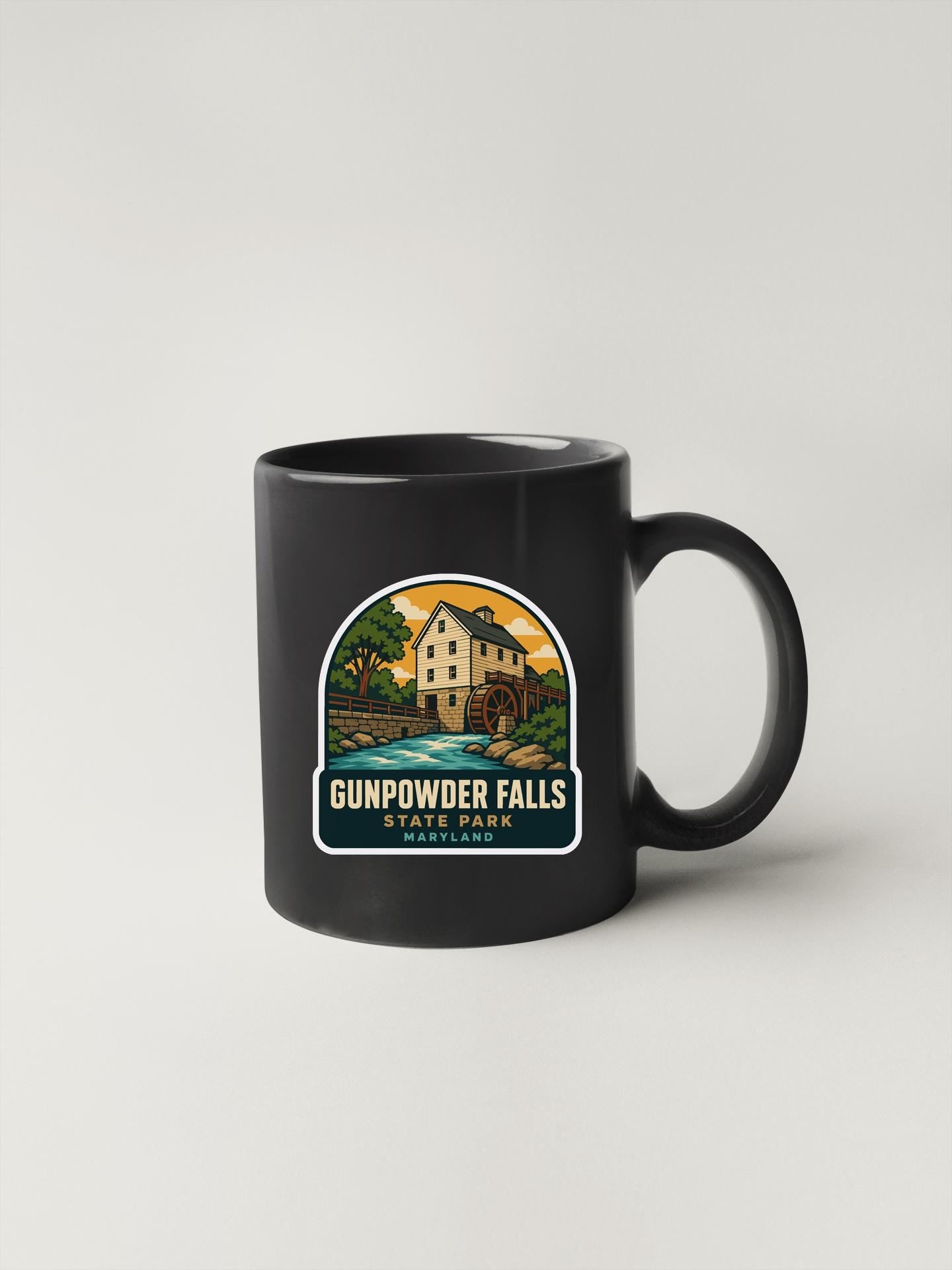 A black coffee mug with a graphic design depicting Gunpowder Falls State Park in Maryland.