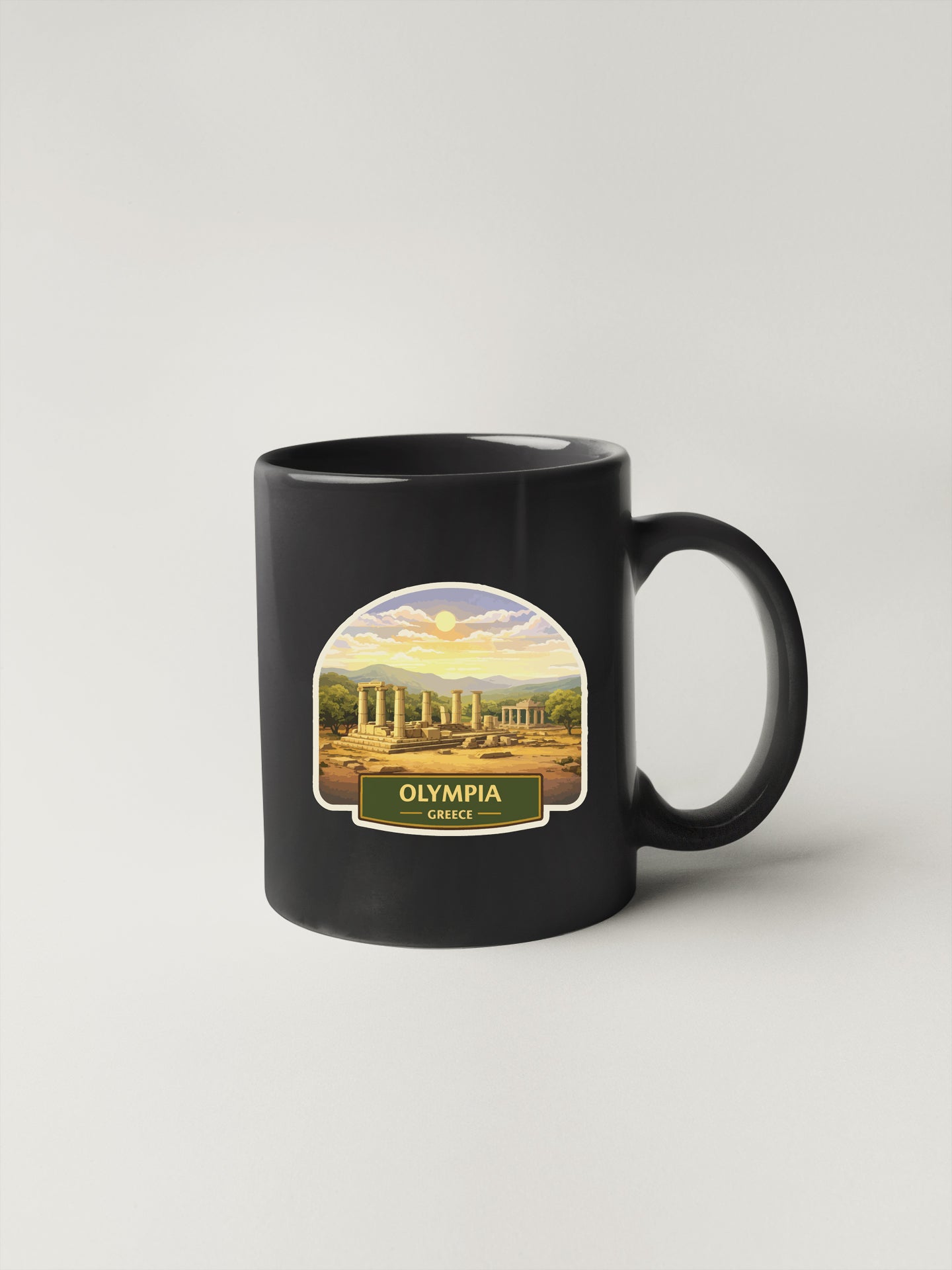 A black coffee mug with a label depicting the city of Olympia, Greece.