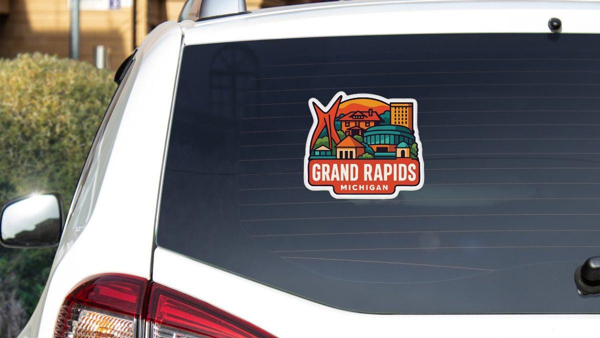 A sticker on the rear window of a white car, depicting a cityscape with buildings and a bridge, along with the text "GRAND RAPIDS MICHIGAN".