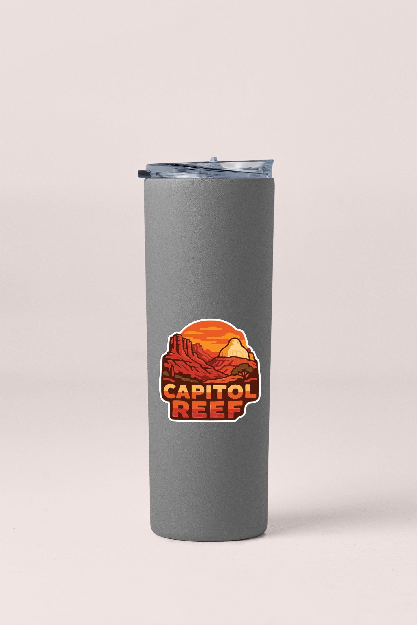 A gray insulated tumbler with a sticker featuring an illustration of a desert landscape and the text "CAPITOL REEF".