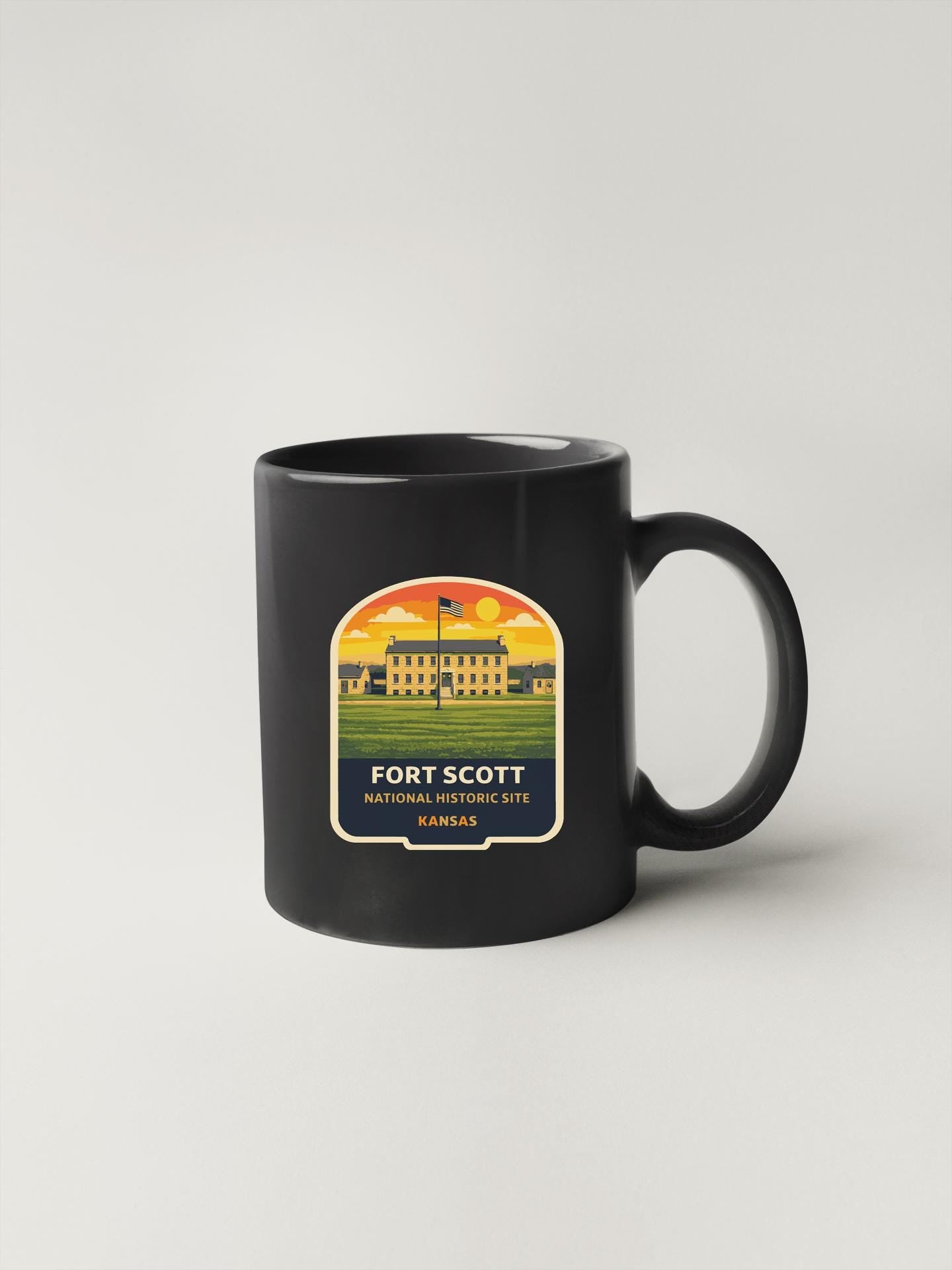 A black coffee mug with a label that says "FORT SCOTT NATIONAL HISTORY SITE KANSAS" printed on it.