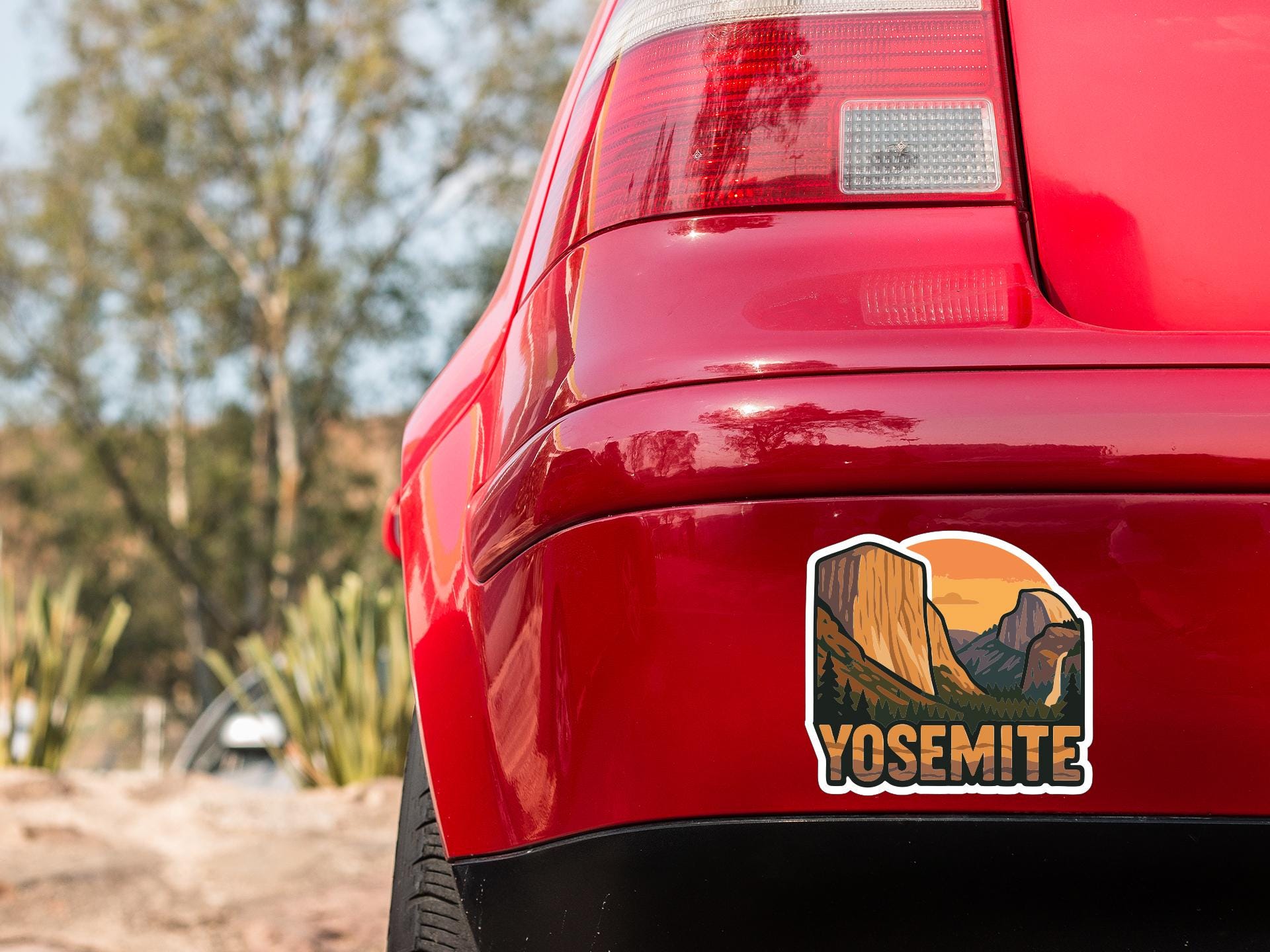 the rear end of a red car with a Yosemite sticker on the trunk.
