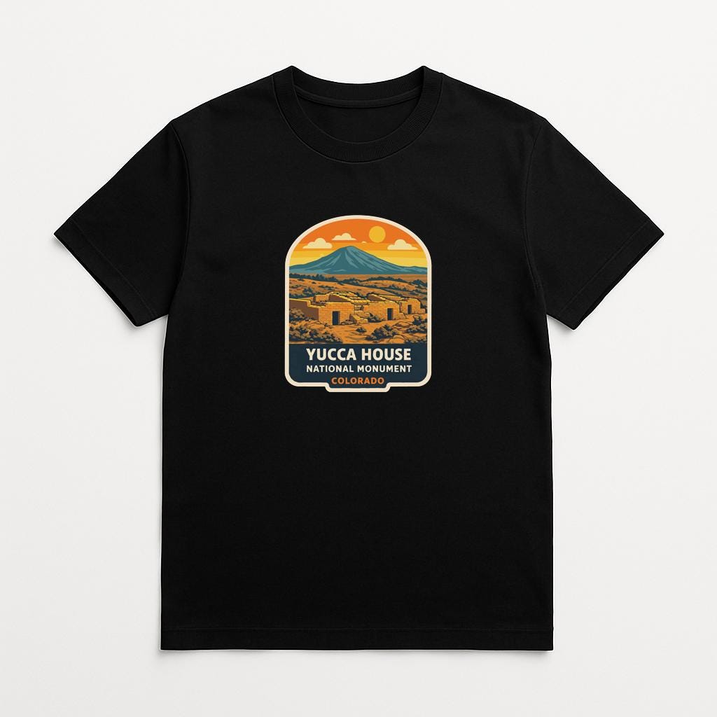 A black t-shirt with a graphic design depicting a mountain landscape with a yellow sun in the sky.
