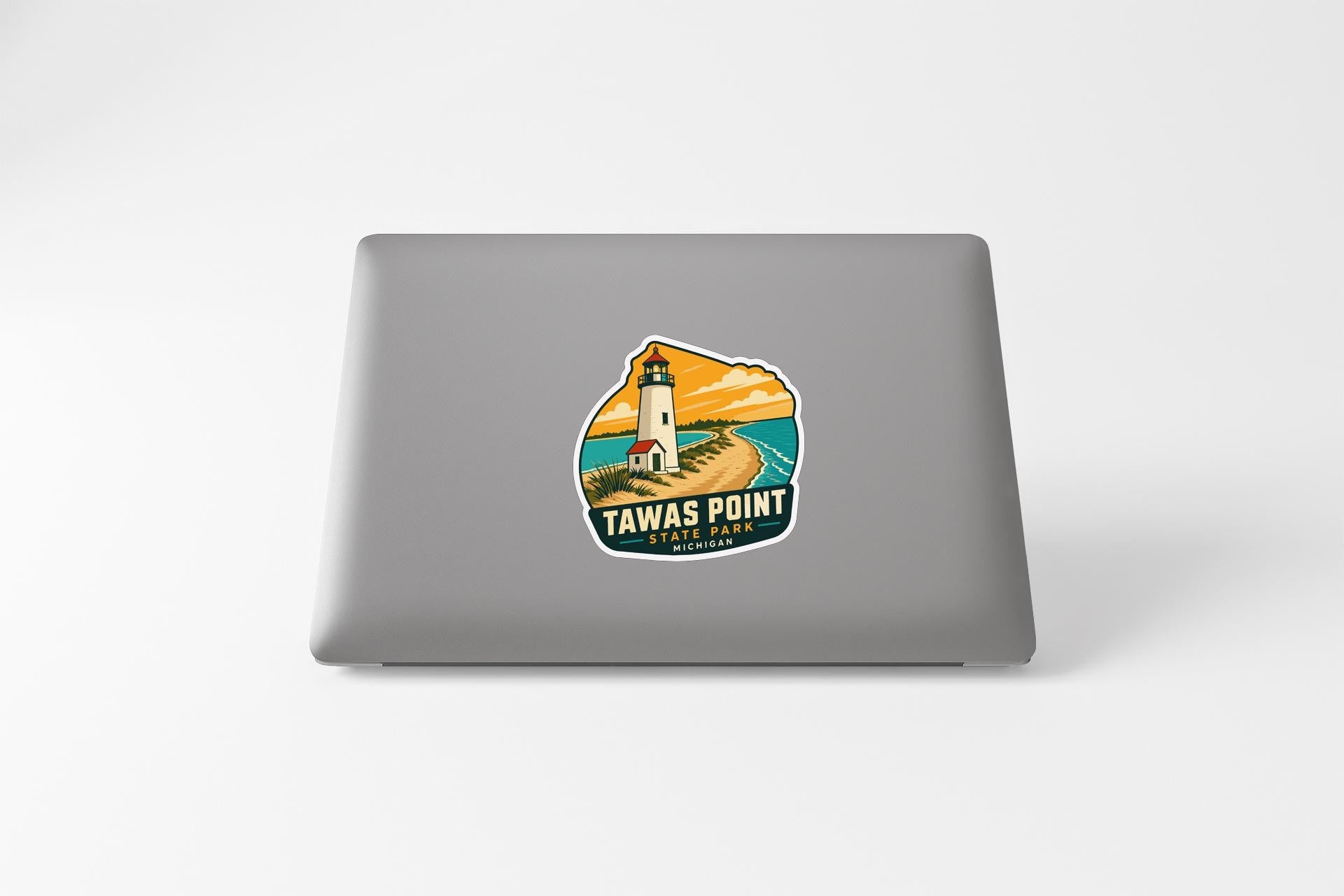 A sticker on the back of a laptop, depicting a lighthouse and a beach scene.