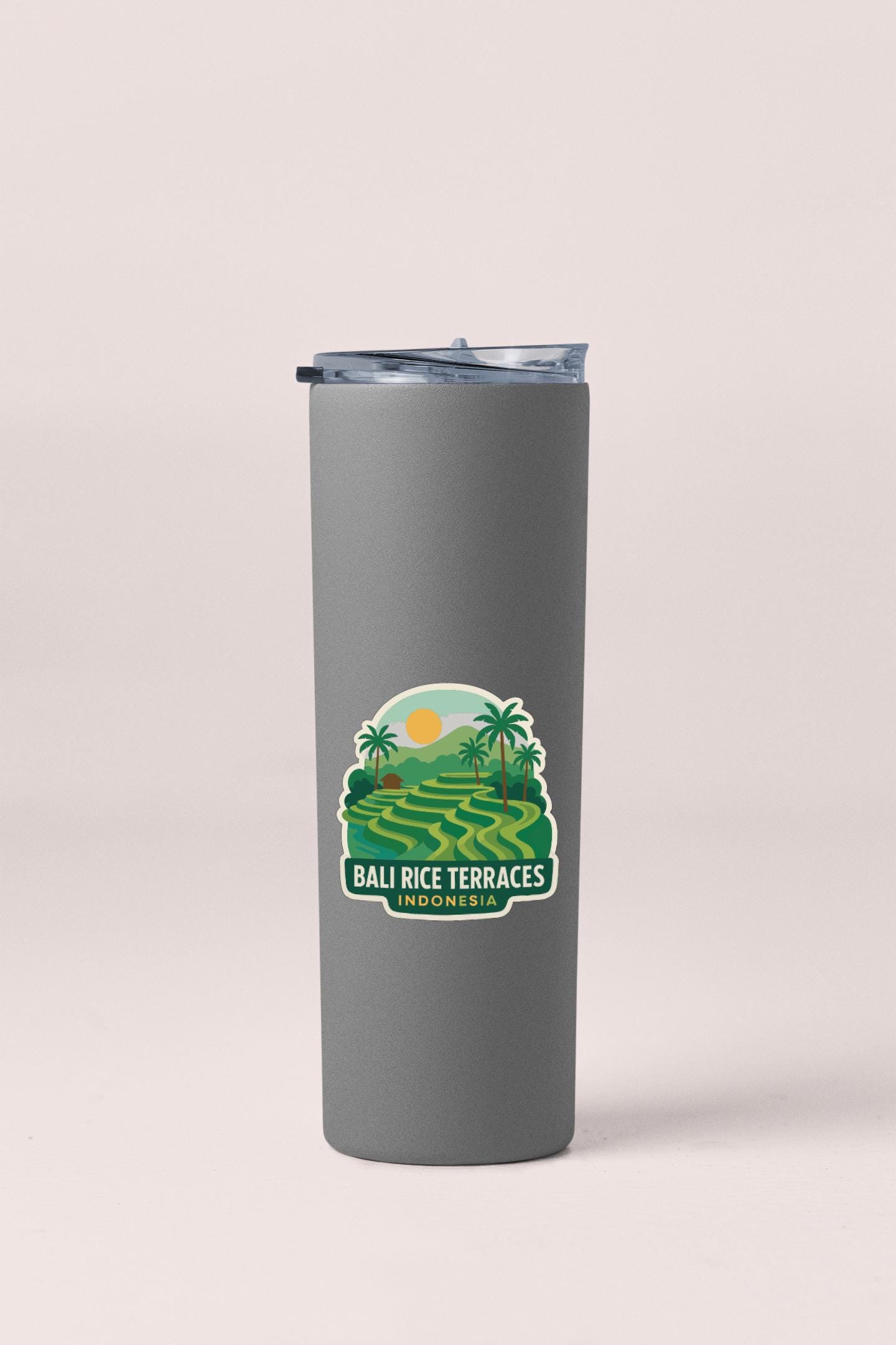 A gray insulated tumbler with a sticker depicting a tropical landscape, including rice terraces and palm trees.