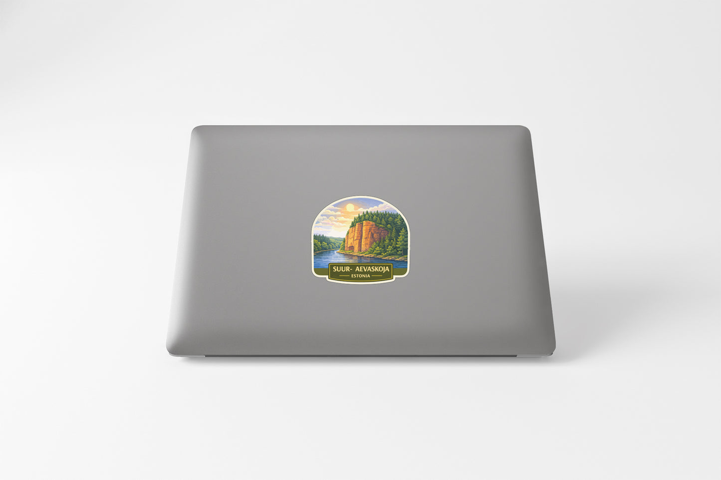 A sticker depicting a scenic landscape with a mountain and a river, placed on the back of a laptop computer.