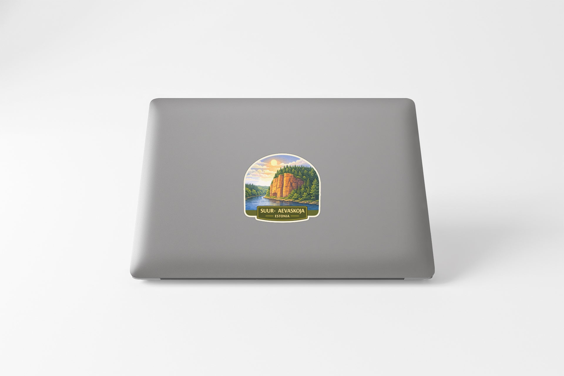 A sticker depicting a scenic landscape with a mountain and a river, placed on the back of a laptop computer.