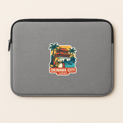 A gray laptop sleeve with a sticker depicting a tropical scene and the text "OKINAWA CITY JAPAN" printed on it.