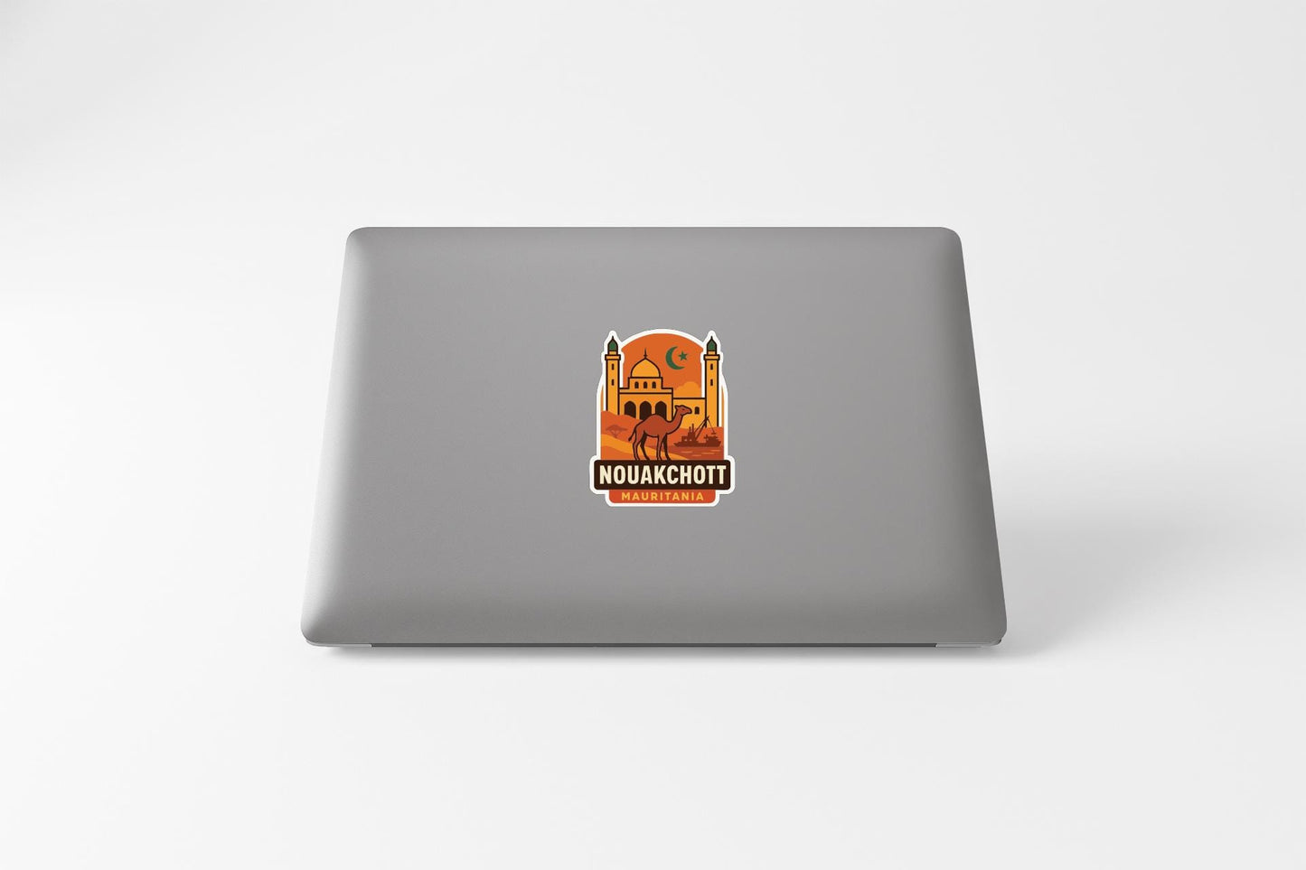 a sticker with an illustration of a building and the text "NOUAKCHOTT" on a laptop.