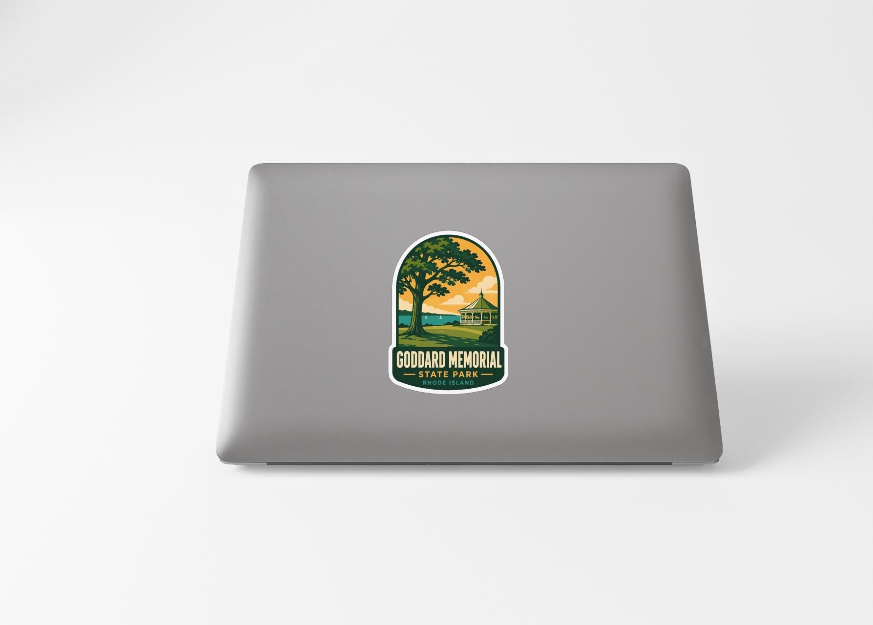 A sticker on the back of a laptop, depicting a scenic landscape with a tree and a building.