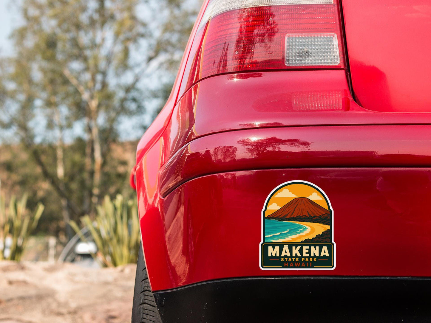 the rear end of a red car with a sticker on the back window that reads "MAKENA STATE PARK, HAWAII".