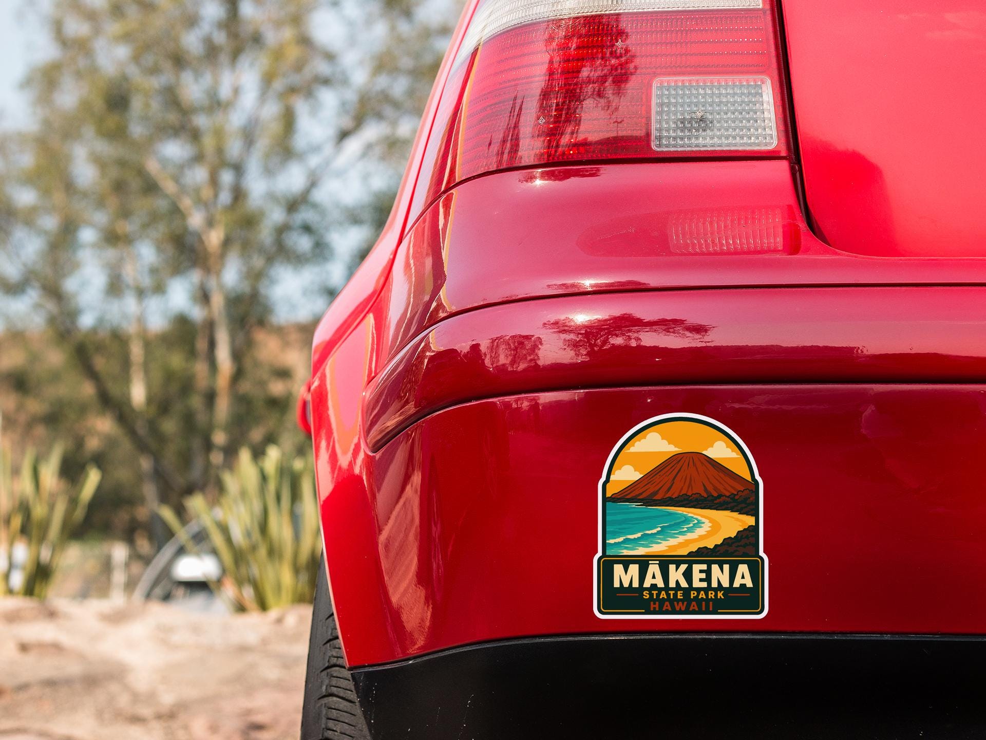 the rear end of a red car with a sticker on the back window that reads "MAKENA STATE PARK, HAWAII".