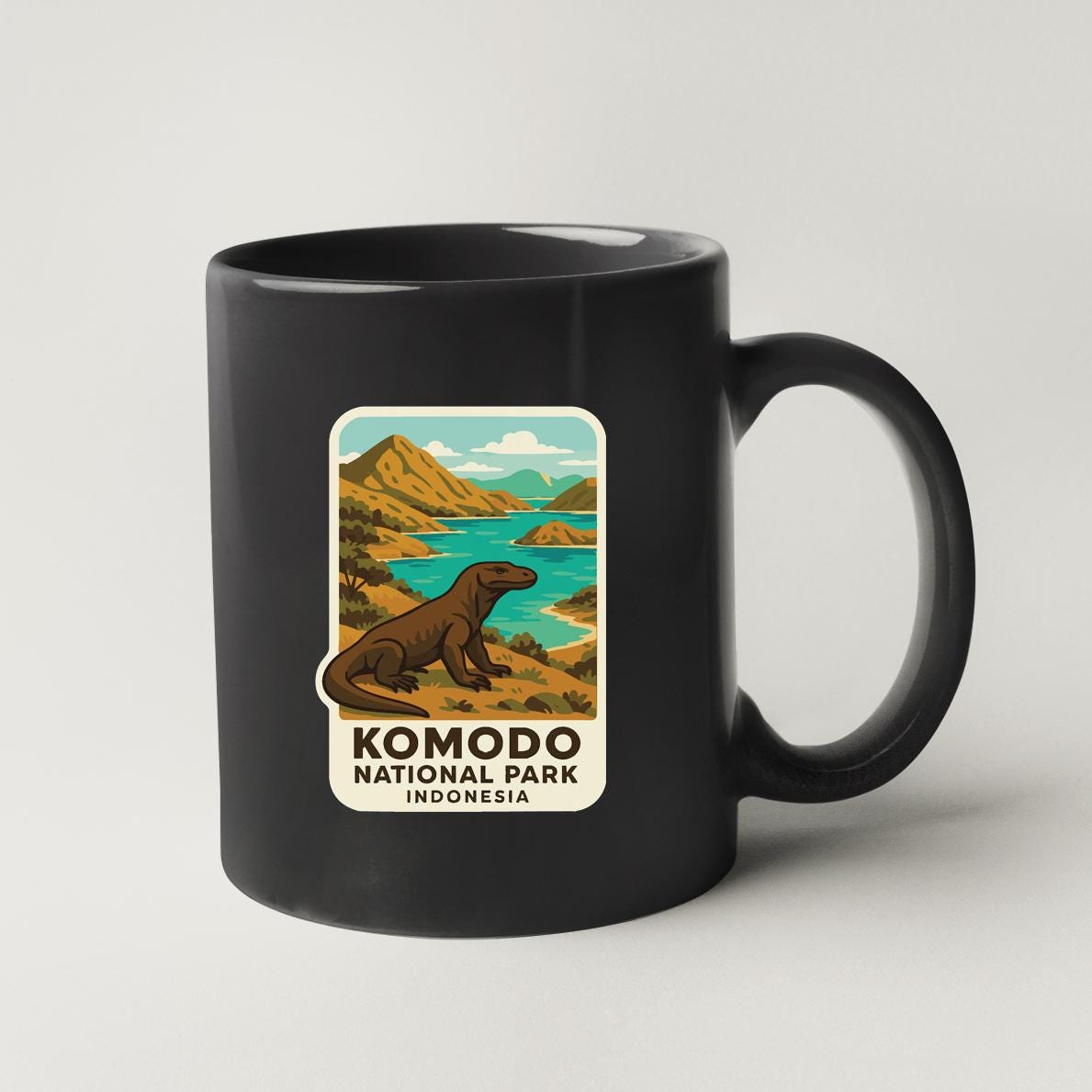 A black coffee mug with a sticker depicting Komodo National Park in Indonesia.