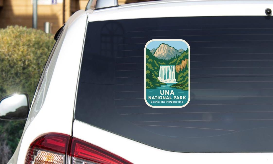 a sticker on the rear window of a white car, depicting a scenic landscape with a waterfall and mountains.