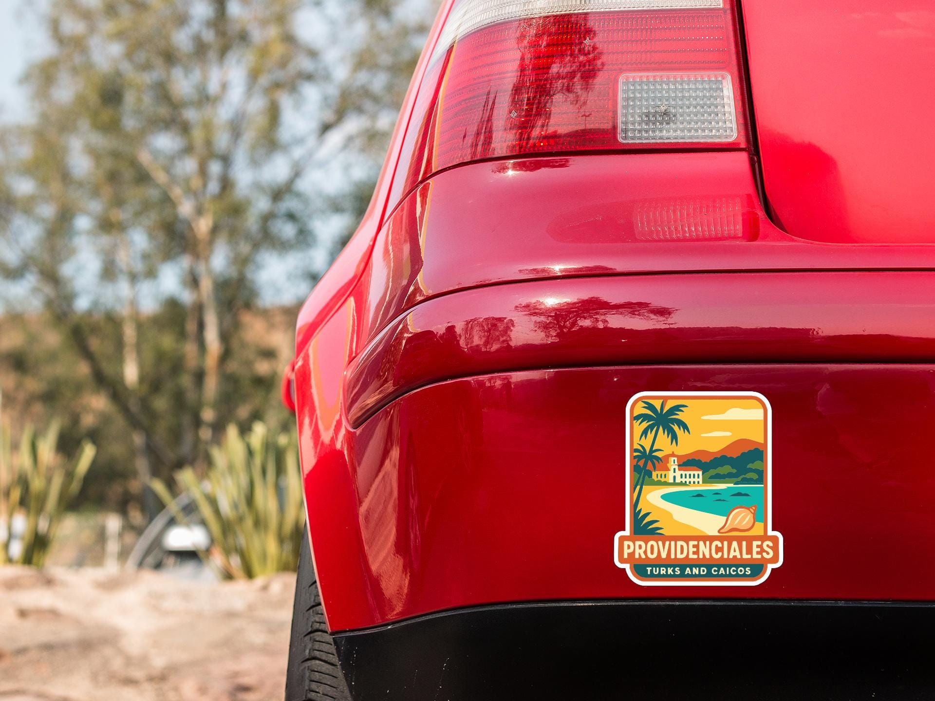 the rear end of a red car with a sticker on the trunk that says "PROVIDENCIALES TURNS AND CAICO".