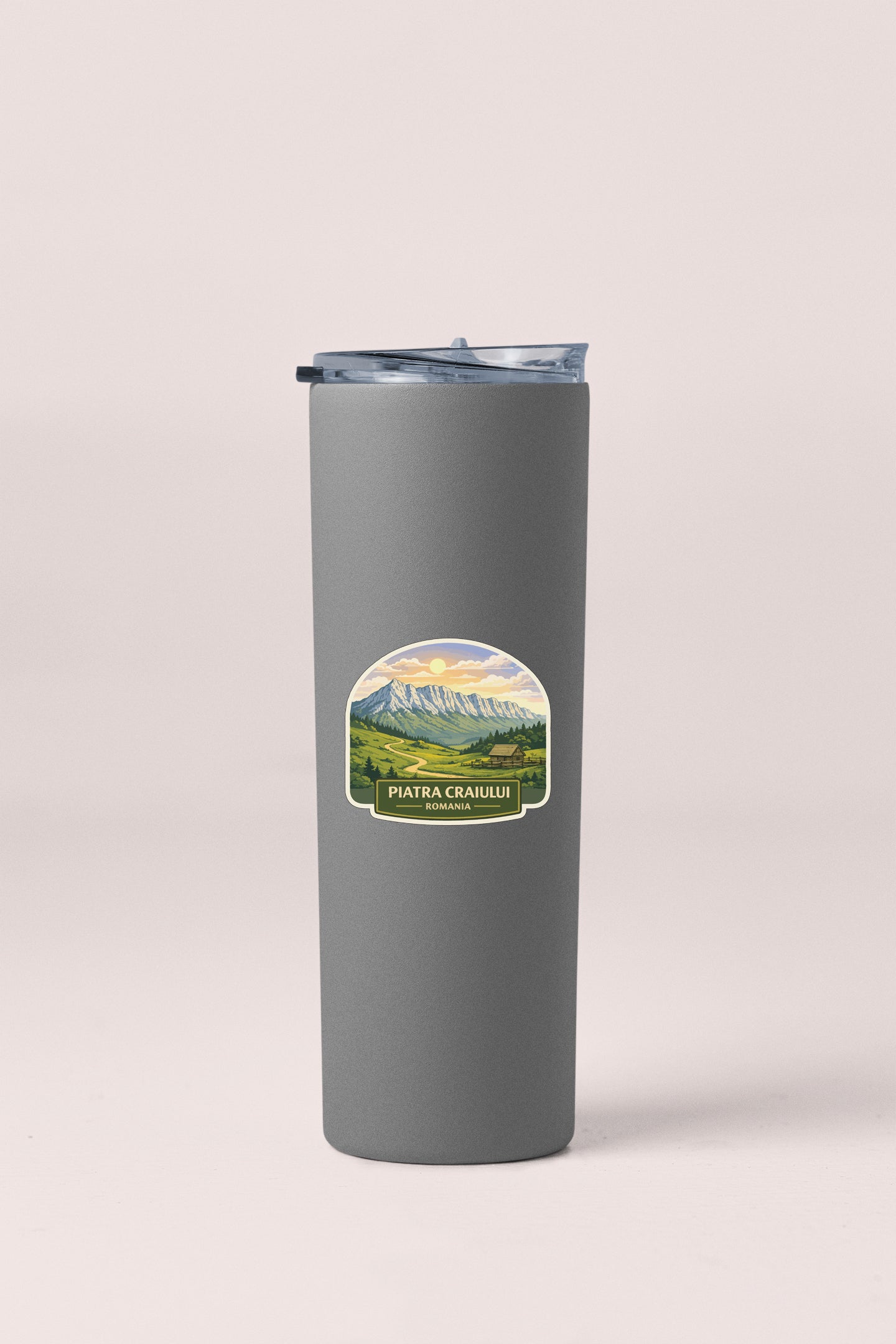 A gray insulated tumbler with a label that features a mountain landscape.