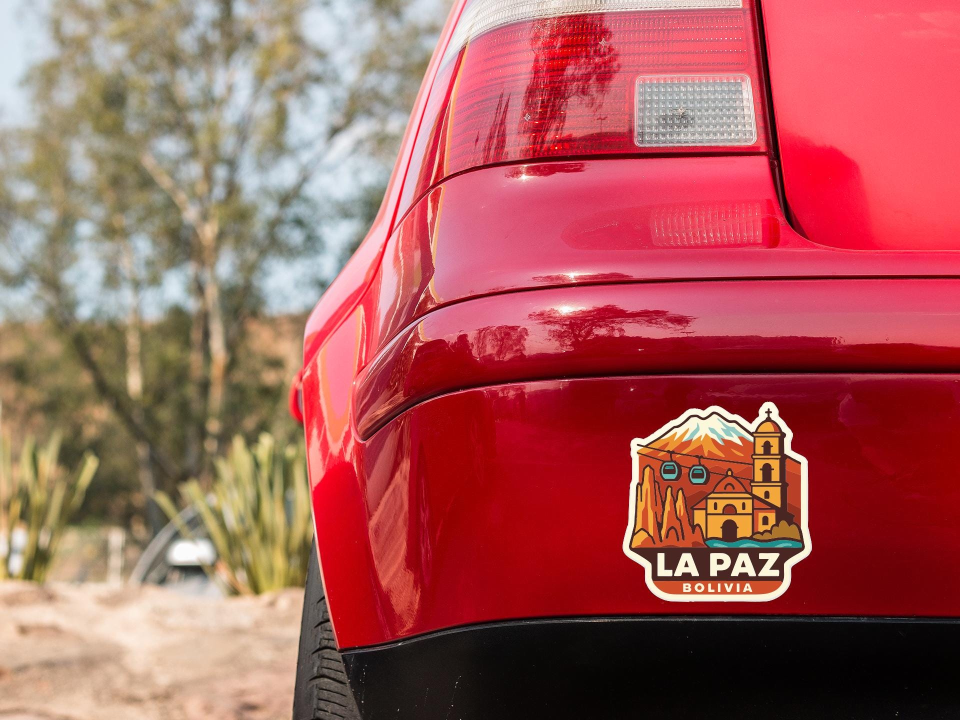 the rear end of a red car with a sticker on the trunk that says "LA PAZ BOLIVIA".