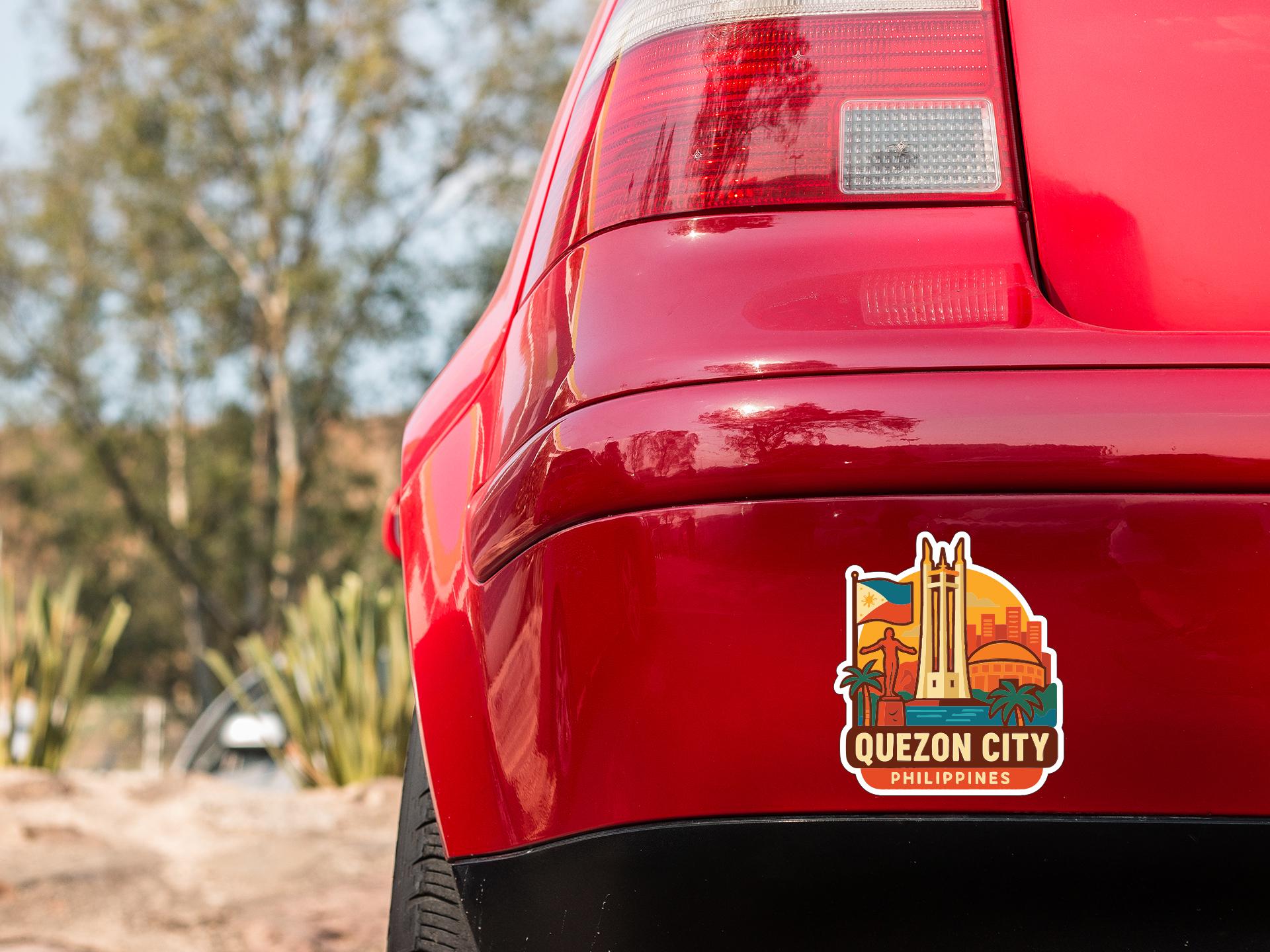 the rear end of a red car with a sticker on the trunk that says "QUEZON CITY PHILIPPINES".