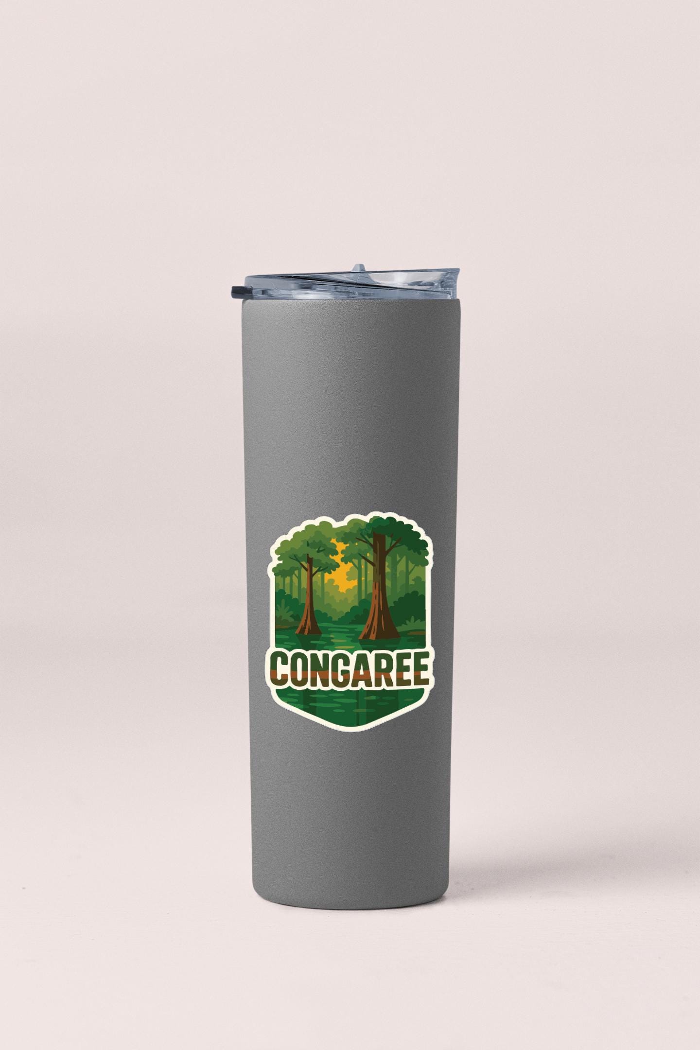 A gray insulated tumbler with a lid and a sticker featuring a forest scene with the word "CONGAREE" written on it.