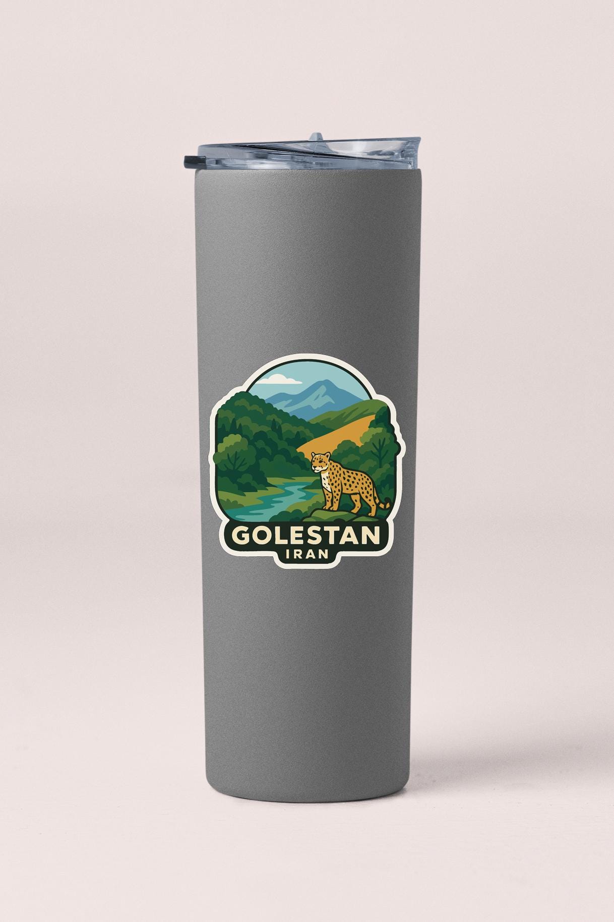 A gray tumbler with a sticker depicting a cheetah and a landscape with mountains in the background.