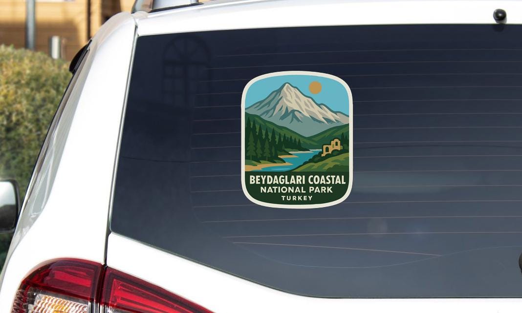 a sticker on the rear window of a vehicle, depicting a scenic landscape with mountains, a river, and a building.