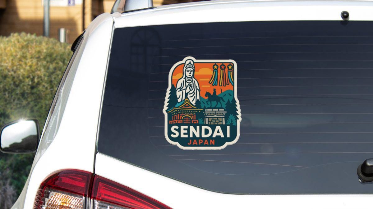 A sticker on the rear window of a white car, depicting a temple and a statue, with the text "SENDAI JAPAN" printed on it.