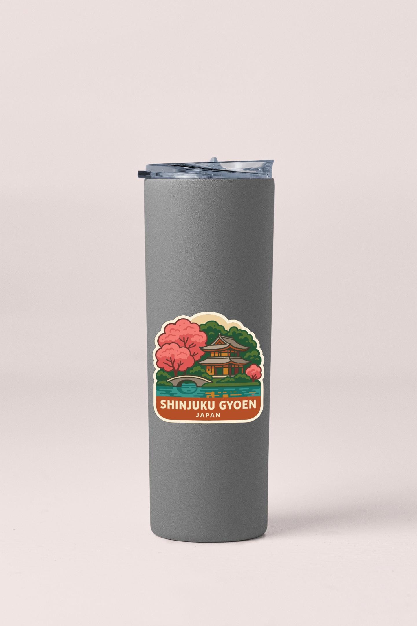 A gray insulated tumbler with a label featuring an illustration of a Japanese temple surrounded by trees and a bridge.