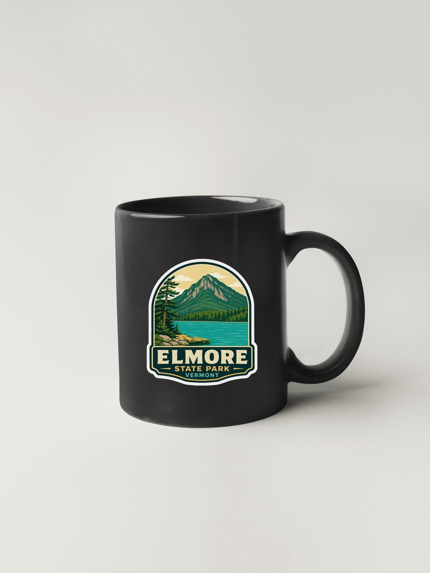 A black coffee mug with a graphic design depicting a mountain landscape and a lake, along with the text "ELMORE STATE PARK, VIRGINIA".